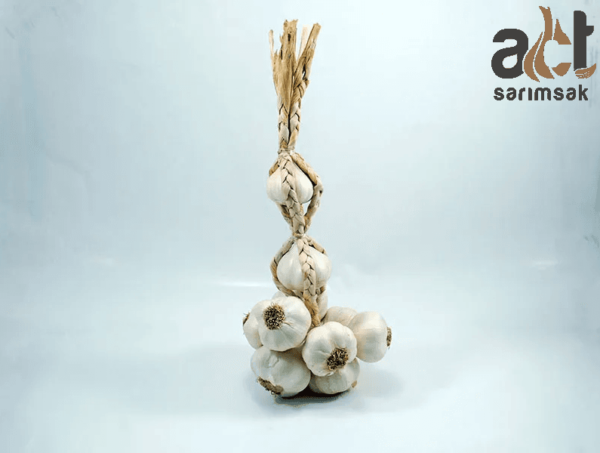 El Bağı Büyük Hakiki Taşköprü Sarımsağı (3KG) soğanlarından oluşan bir demet, örgülü samanla bağlanmış, açık renkli bir arka plan üzerinde dik durmaktadır. Sağ üst köşede "act sarımsak" logosu yer almaktadır.